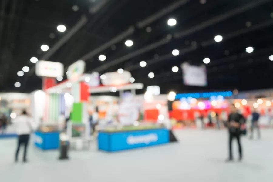 A packed tradeshow with a tabletop display, blurred.